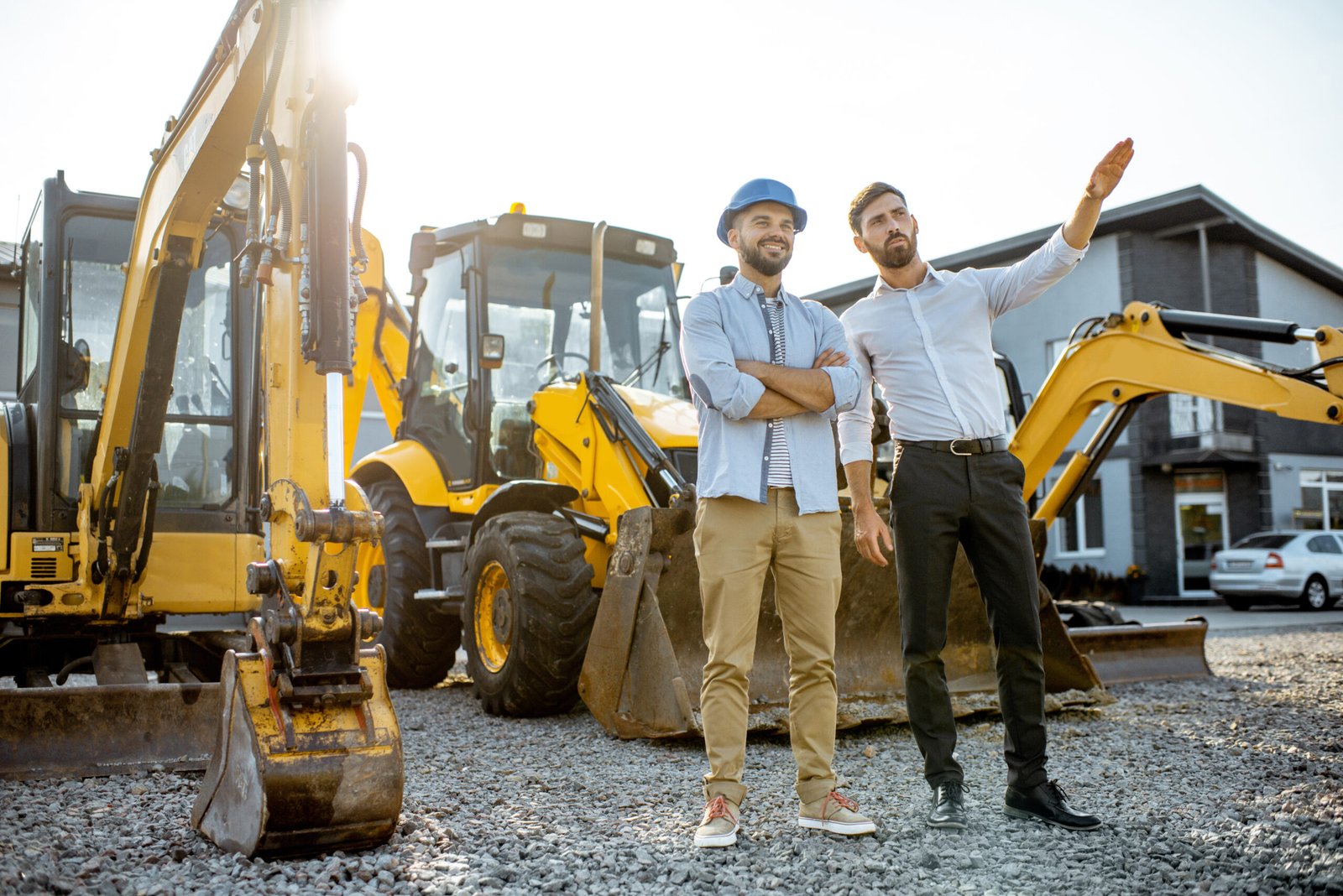 Builder choosing heavy machinery for construction with a sales consultant on the open ground of a shop with special vehicles